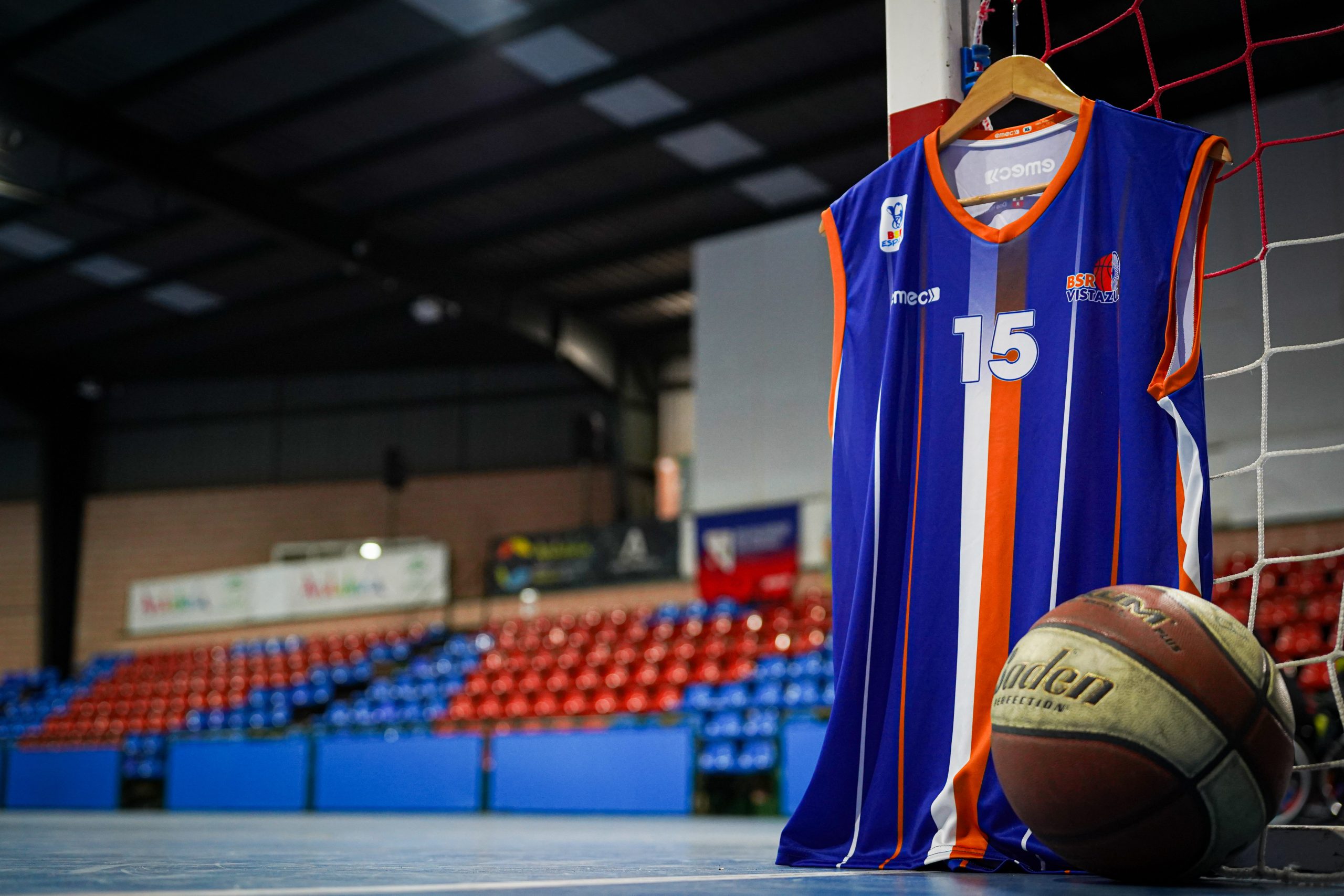 Foto profesional de la camiseta del club BSR Vistazul colgada en una portería en las instalaciones de Vistazul con las gradas de fondo